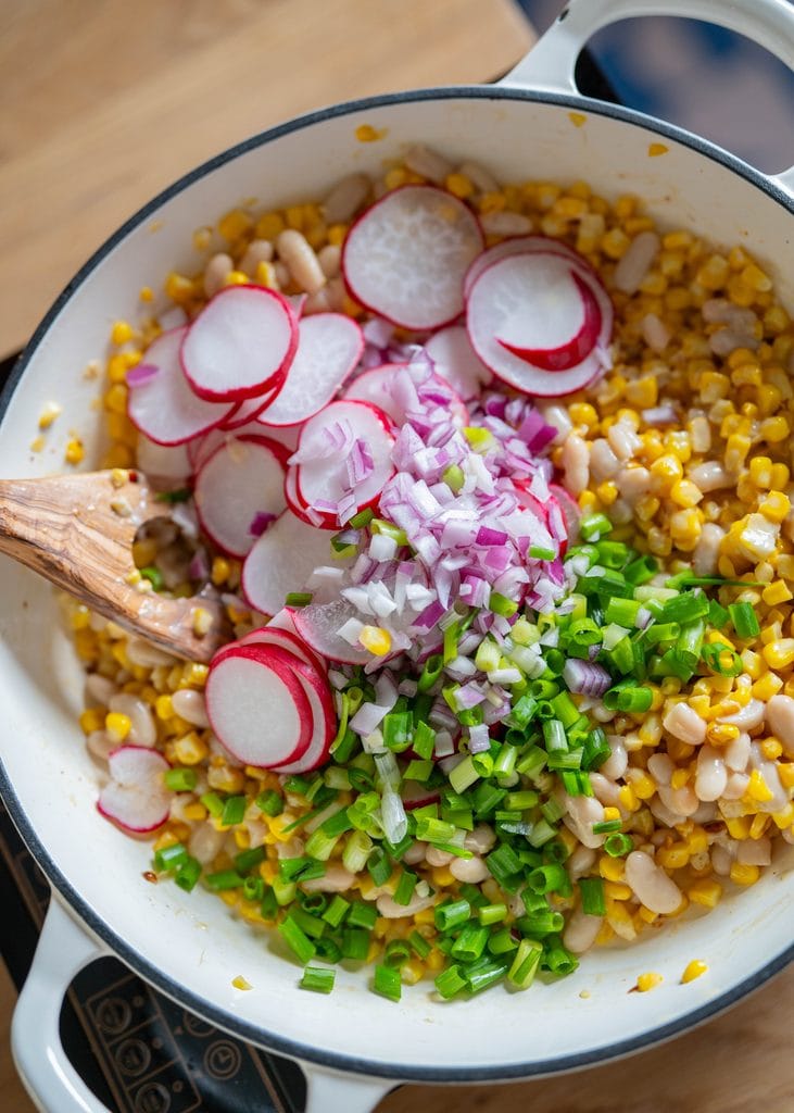 adding in vegetables to skillet