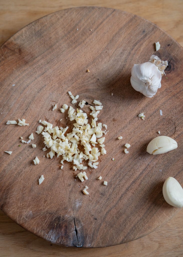minced raw garlic on cutting board