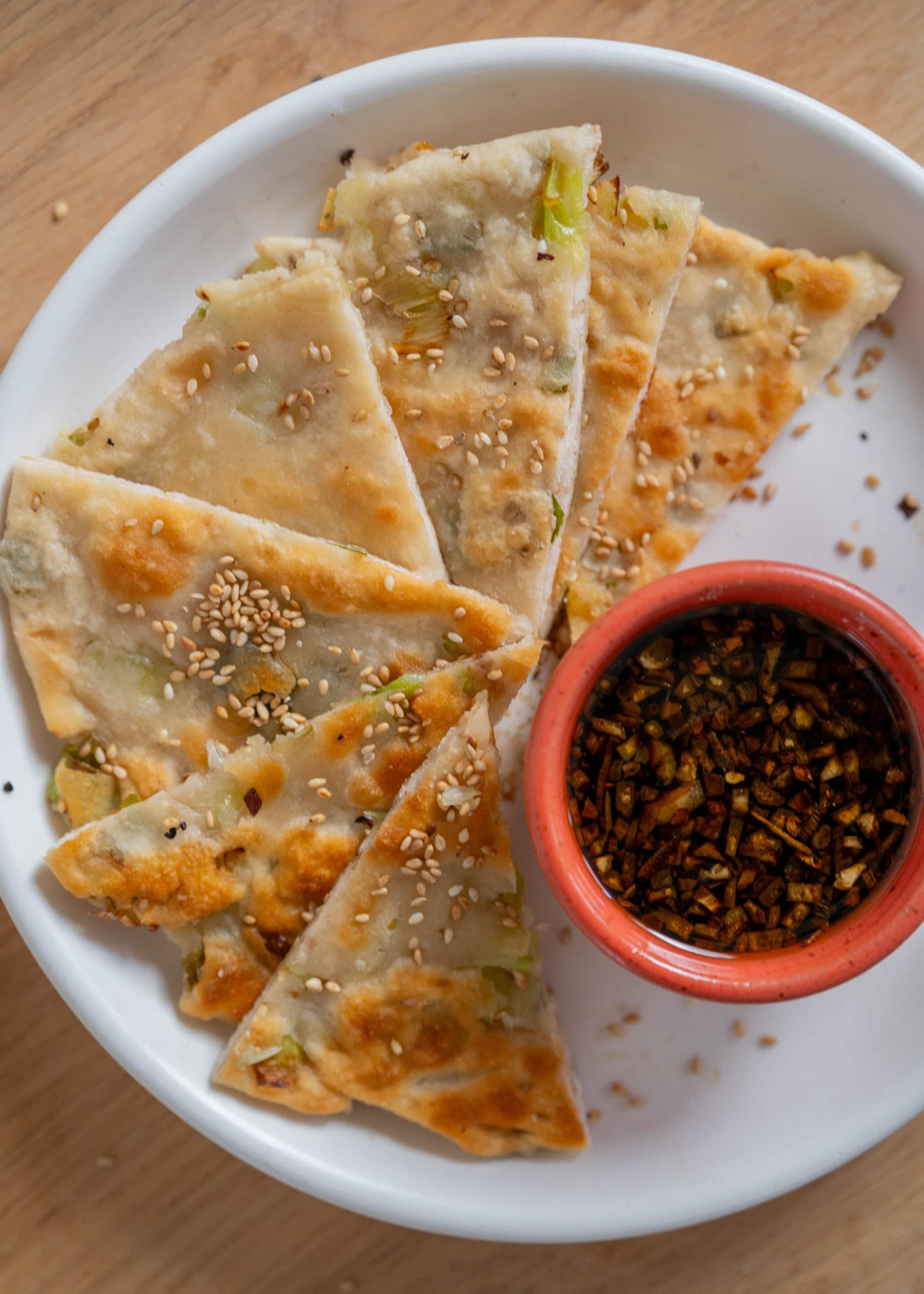 sourdough discard scallion pancakes sliced into triangles with dipping sauce on side