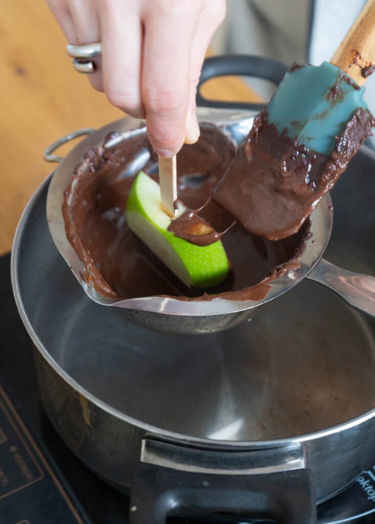 dipping apple slice in melted chocolated
